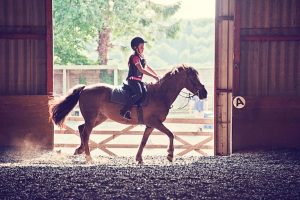 Niño montando caballo ilustrando beneficios de la equitación